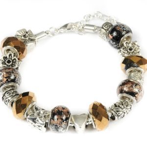 Introducing the Bronze Beauty Bracelet: a stunning silver charm bracelet adorned with a variety of exquisite beads and charms. The bracelet showcases faceted bronze-colored beads, glittery black and copper speckled pieces, and intricate floral silver ornaments. Charms include captivating designs such as a star, a heart, and beautiful floral motifs, all elegantly set against a white backdrop.