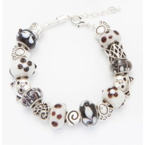 The Cat's Meow Bracelet features a stunning blend of alternating black, white, and silver beads decorated with swirls, polka dots, and intricate designs. This elegant silver bracelet is equipped with an adjustable clasp and an extender chain for a perfect fit.