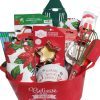 A red Automotive Basket with "Believe in the magic of Christmas" text contains festive kitchen items including cookie cutters, a festive towel, a whisk, straws, a tree-shaped spatula, a mixing bowl, and other baking accessories adorned with Christmas decorations.