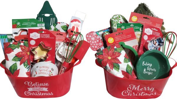 Two Automotive Baskets, resembling festive containers, are filled with assorted Christmas-themed kitchen items like cookie cutters, spatulas, whisks, pot holders, and napkins. One basket has "Believe in the magic of Christmas" text and the other says "Merry Christmas." Festive packaging and decorations are visible.