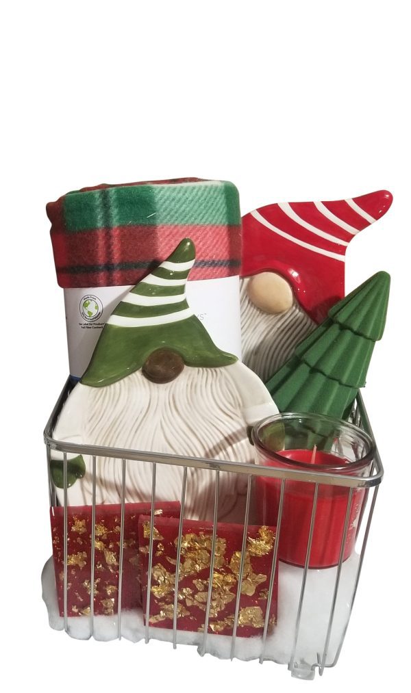 A festive gift basket featuring the Automotive Basket, which includes a red and green Christmas blanket, ceramic gnome figures in red and green hats, a green tree-shaped ornament, a red and white candle in a glass holder, and a red gift box with gold decorations—all perfectly organized in an automotive-themed metal wire basket.