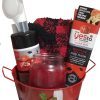 The Automotive Basket, adorned with a festive Santa outfit design, contains a face mask applicator, a bottle of facial cleanser, a tube of detoxifying mud mask, a red and black knitted cloth, and a red jar candle.