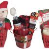 Three holiday gift baskets, each containing assorted self-care items. Baskets include aloe-infused socks, candles, face masks, bath scrubs, toothpaste, and plush toys, all festive in red containers. Each basket has a theme: Santa Basket with jolly accessories; an Automotive Basket for car enthusiasts with automotive goodies; and a Facial Care Basket focusing on skincare essentials.