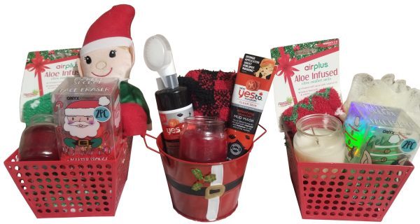 Three holiday gift baskets, each containing assorted self-care items. Baskets include aloe-infused socks, candles, face masks, bath scrubs, toothpaste, and plush toys, all festive in red containers. Each basket has a theme: Santa Basket with jolly accessories; an Automotive Basket for car enthusiasts with automotive goodies; and a Facial Care Basket focusing on skincare essentials.