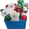 A blue Automotive Basket filled with various dog toys and treats, including plush holiday-themed items such as a snowman, a bear, and a sheep, plus a bag of OluPet Healthy Bites chicken-flavored dog treats. The toys are adorned with festive colors and patterns.