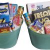 Two mint-green Automotive Baskets are filled with various board games, snacks, and popcorn packs. Visible games include "Telestrations," "Snakes and Ladders," "Pictionary," and "TelegraV." These baskets appear ready for a fun game night that will rev your excitement like an automotive engine.