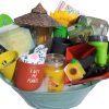 An Automotive Basket brimming with gardening-themed delights: a candle, yellow flower picks, a small watering can with "I wet my plants" text, garden gloves, a mini garden tool set, plant markers, a teal pot, gardening clippers, a sunflower decoration, and more. Perfect for the green thumb in your life!