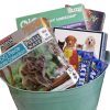 A light green Automotive Basket containing several items, including jigsaw puzzles with images of koalas and puppies, a "Robot Workshop" kit, a book titled "Star Wars," and packs of Wacky-Brand balloons. The basket is filled with various colorful educational and fun activities.