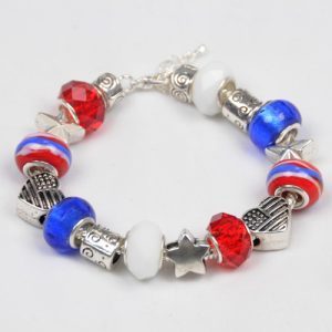 The Stars & Stripes Patriotic Bracelet showcases a mix of beads and charms in vibrant red, white, and blue hues. Featuring both faceted and smooth beads adorned with decorative metallic accents, this bracelet includes heart, star, and cylinder-shaped charms with intricate designs that embody a patriotic spirit.