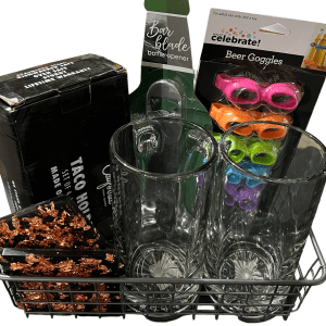 The Epic Women's Spa Basket includes two tall glasses, four colorful beer goggles, a black Taco Holders set box, a Bar Blade bottle opener, and a decorative item with a black base and metallic rose gold flakes. All items are beautifully arranged in a chic metal wire basket.