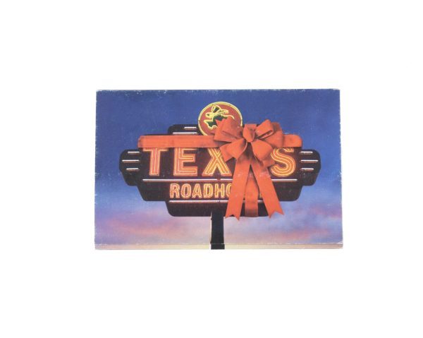 A bright neon Texas Roadhouse sign adorned with a large red bow sets the scene against a twilight sky; the letters glowing in yellow and red enhance its roadside appeal and hint at the cozy atmosphere within. Get the Kitchen & Home Large set, which includes $50 in Texas Roadhouse Certificates, for an unforgettable dining experience.