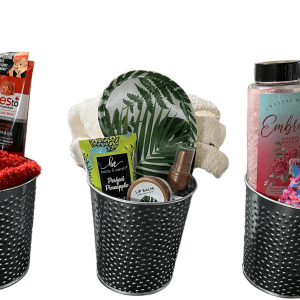 Three gift baskets with self-care products in black perforated metal containers. The left basket, labeled as the Epic Women's Spa Basket, contains a red towel, face mask, and brush. The middle basket includes a tropical-themed dish, lip balm, and scrunchie. The right basket offers lotion, bath salt, and watermelon-themed items.