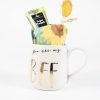 The You are my BFF Mug Gift Basket with Free Food Certificate features a white mug adorned with gold letters spelling "BFF" and the text "you are my" at the top, filled with a yellow lollipop, a pineapple-flavored candy packet, and a colorful sunflower-themed towel. This delightful gift set is the perfect addition to any gift basket and stands out beautifully against a plain white background.