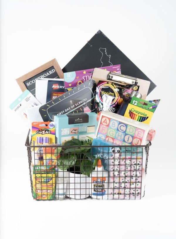 The Adult Gambling Night Basket is filled with a wire basket containing various items for organizing your event, including crayons, notebooks, stickers, glue, pencils, a ruler, ABC flashcards, a plant, and decorative items. Perfect for adults planning an educational fun night in. The assortment also features a scoreboard and a state-shaped chalkboard.