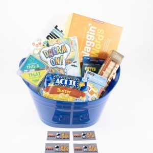 A blue gift basket, known as the "Big Air Trampoline & Pizza Entertainment Basket," is filled with assorted items including snacks, a book titled "Haggin' Words," a game called "Dream On!", popcorn, candy, and various entertainment coupons. Three pizza coupons are displayed in front of the basket.