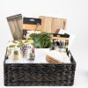 The Personalized Kitchen & Home Gift Basket features a variety of kitchen and bar items, including a bar spoon with a garnish fork, a cutting board set, two custom coasters, a plant, a grape-design kitchen towel, two custom glasses, and a jar.