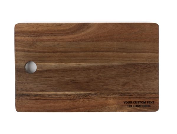 A rectangular wooden cutting board, featuring a smooth surface and a cut-out handle on the top left corner. The bottom right corner includes an area for custom text or logo engraving, making it perfect for personalization. This essential component of the Personalized Kitchen & Home Gift Basket, which also includes 2 custom glasses and 2 custom coasters, showcases a beautiful natural wood grain pattern.