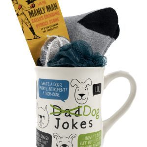 The Dog Jokes Mug Gift Basket with Free Food Certificate features a blue loofah, gray socks, a Free Food Certificate, and a yellow package labeled "Manly Man Callus Grinder." The mug showcases a cartoon dog face along with text bubbles containing corny dog-themed dad jokes.