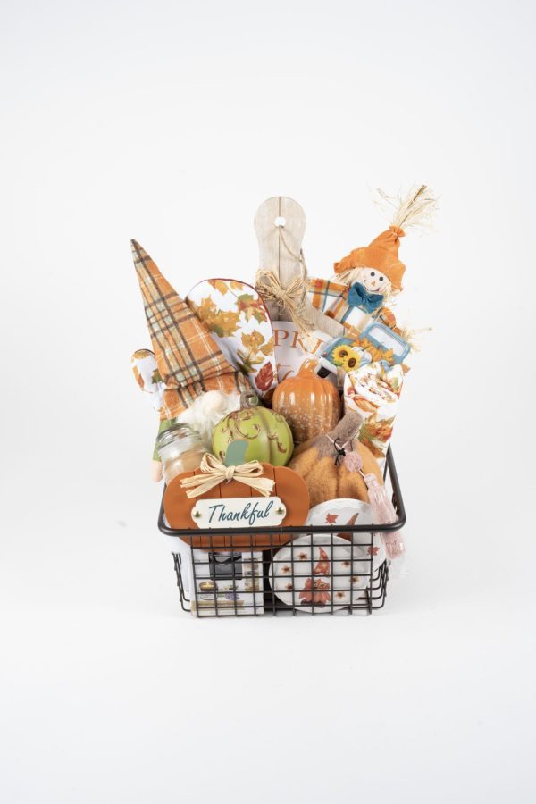 The Fall Harvest Gift Basket - Medium is filled with various items including pumpkins, a "Thankful" sign, autumn leaves, a plaid napkin, a scarecrow, a mini cutting board, and sunflower accents. This delightful gift basket celebrates the fall harvest season and Thanksgiving.