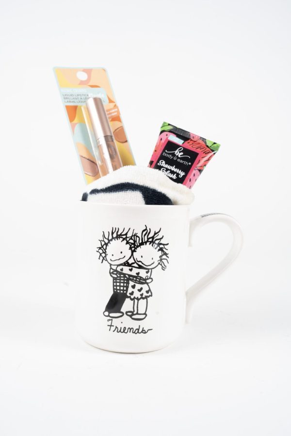 The Friends Mug Gift Basket With Free Food Certificate includes a white ceramic mug featuring a black-and-white illustration of two embracing stick-figure friends labeled "Friends." Inside the mug, you'll find a pair of socks, metallic pink liquid lipstick in its packaging, and a small tube of hand cream with a colorful design—all perfect for creating an adorable gift basket.