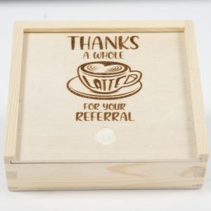 Introducing the "Gift Box - Thanks a Whole Latte for your Referral," featuring a wooden design with a sliding lid. Engraved on the lid is an illustration of a coffee cup with latte art, accompanied by the phrase "THANKS A WHOLE LATTE FOR YOUR REFERRAL.