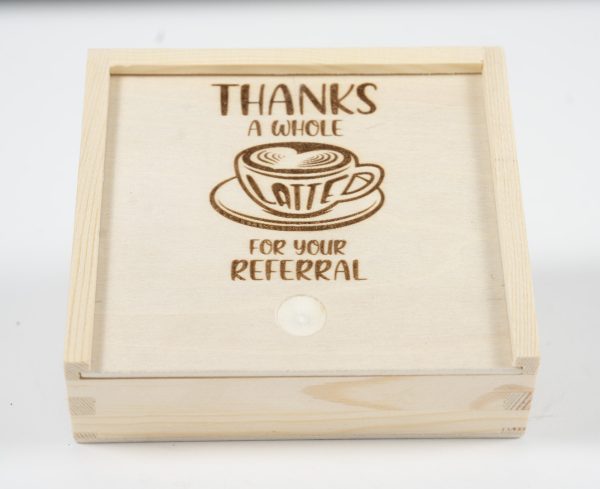 Introducing the "Gift Box - Thanks a Whole Latte for your Referral," featuring a wooden design with a sliding lid. Engraved on the lid is an illustration of a coffee cup with latte art, accompanied by the phrase "THANKS A WHOLE LATTE FOR YOUR REFERRAL.