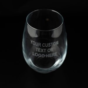 Transparent glass from the "Pair of Wine Glasses - Your Custom Text/Logo Here" set, featuring an engraving that reads "YOUR CUSTOM TEXT OR LOGO HERE" against a black background, ideal for personalized wine glasses.