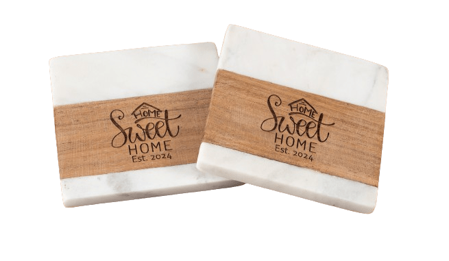 Two rectangular marble coasters with wooden accents. Each coaster has the phrase "Home Sweet Home Est. 2024" engraved on the wooden part. The design includes a small house icon atop the text.