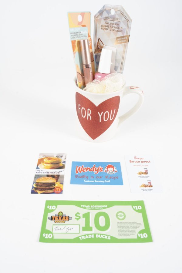 A white mug labeled "FOR YOU," filled with nail polishes, a nail file, a bath sponge, and gift cards, is displayed on a white background. Named the For You Love Mug Gift Basket with Free Food Certificate, in front of the mug are gift cards from McDonald's, Wendy's, Texas Roadhouse, and a free food certificate from Wendy's.