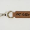 Introducing the Custom Key Chain - Laser engraved on one or Both Sides, crafted from high-quality brown leather and equipped with a sturdy metal keyring and clip. This elegant keychain features professionally laser-engraved logos along with the text "eXp Realty" and "Ohio Housing Experts" on both sides of the strap. The keyring connects seamlessly to both the strap and the clip, creating a cohesive, stylish accessory against a plain white background.