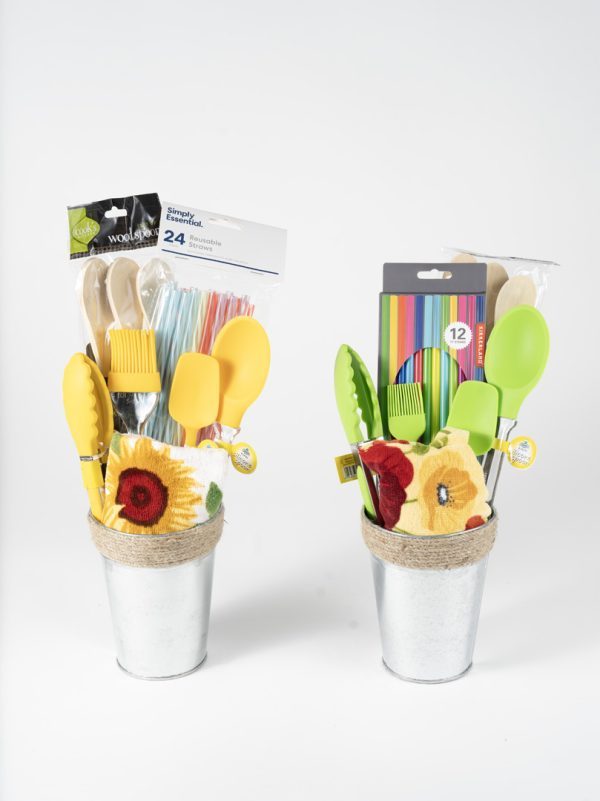 The Adult Gambling Night Basket features two metallic pails filled with kitchen essentials and biodegradable striped straws. One pail contains yellow and green silicone utensils, while the other includes an assortment of yellow and green utensils, colored pencils, and an elegant touch suitable for a sophisticated adult evening. Both pails are adorned with decorative cloth flowers and wooden utensils.