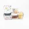 A wire basket contains a rolled-up fleece throw with a floral design, a floral-themed card, custom coasters, and a yellow glass candle. The items are arranged neatly against a white background, making it an ideal Personalized Kitchen & Home Gift Basket with 2 Custom Coasters for any occasion.