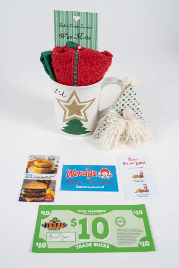 The Christmas Glitter Tree Mug Gift Basket features a shimmering mug adorned with a gold star and the word "Lit," brimming with red and green towels. Accompanying the mug are a charming gnome ornament, a heartfelt note, and gift cards from Wendy's, Chick-fil-A, McDonald's, and Texas Roadhouse—making it an ideal choice for a Christmas gift basket.