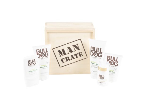 A wooden crate labeled "Man Crate Gift Box" is surrounded by Bulldog skincare products, including After Shave Balm, Original Face Wash, Protective Moisturizer SPF 15, and Two-in-One Beard Conditioner. This gift box sits against a white background.