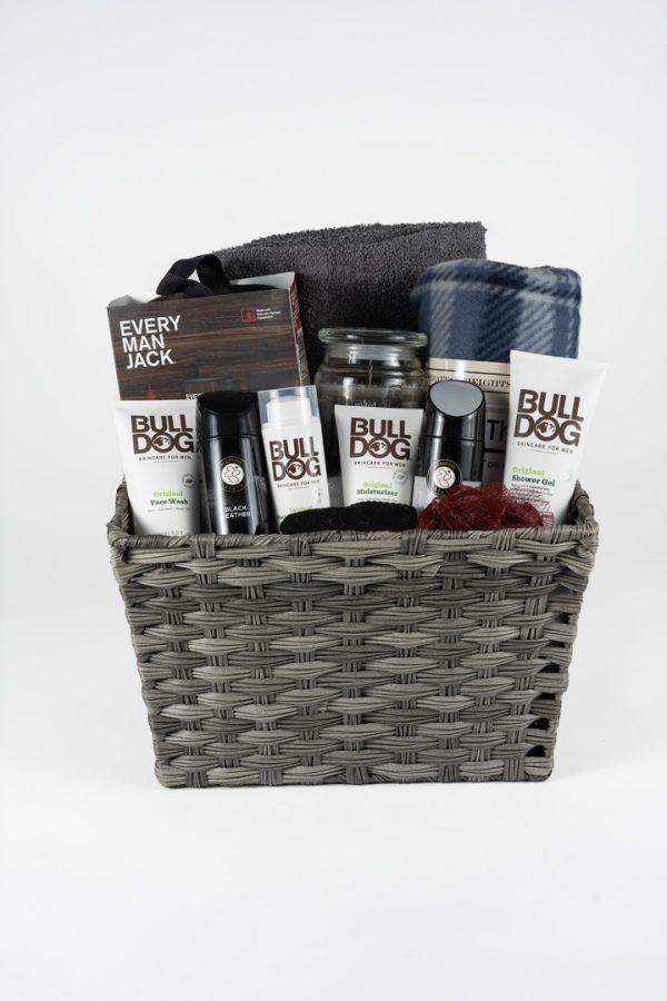 The Adult Gambling Night Basket contains various men's grooming products, such as lotion, deodorant, body wash, and moisturizer from Bulldog brand. It also includes an Every Man Jack grooming kit. Additionally, the basket features a rolled gray towel, a small checkered blanket, and a brown sponge—perfect for any adult's daily routine.