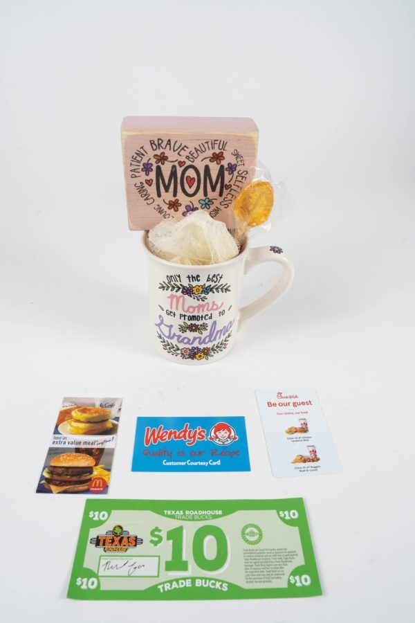 The Promoted to Grandma Mug Gift Basket with Food Certificates includes a charming mug adorned with floral designs and the heartfelt message, "The best Moms get promoted to Grandma." Inside, you'll discover a beautifully decorated wooden block that says "Mom" and a delicious cookie. Additionally, it comes with an assortment of food certificates for McDonald's, Wendy's, Chick-fil-A, and Texas Roadhouse.