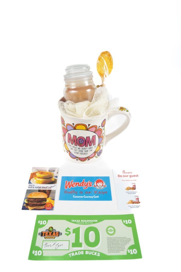 A vibrant "Mom We Know I'm Your Favorite" mug filled with a jar of cocoa mix and a lollipop, elegantly wrapped in lace cloth. Nestled around the mug are gift cards for McDonald’s, Wendy’s, Chick-fil-A, and a $10 Texas Roadhouse Trade Bucks certificate—crafting the ideal Mom We Know I'm Your Favorite Mug Gift Basket with Free Food Certificate.