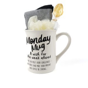 The Monday Mug Gift Basket with Free Food Certificate includes a white mug adorned with the text "A wish for the week ahead. May you meet your challenges with grace and may your patience and coffee be strong..." Inside, you'll find a gray sock, a black sock, a yellow loofah, and a lollipop. This delightful gift basket makes for an ideal start to any week.