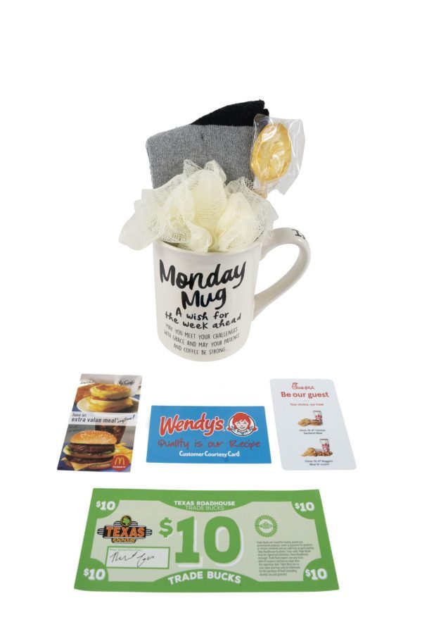 The "Monday Mug Gift Basket with Free Food Certificate" features a white mug adorned with the text "Monday Mug" in black, filled with a loofah, a pack of socks, and a small round soap. Beneath the mug lies a gift basket containing free food certificates and coupons from Wendy's, McDonald's, Texas Roadhouse, and Chick-fil-A.