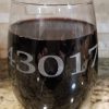 A pair of **Pair of Wine Glasses - Choose any Zip Code**, each etched with the zip code "43017" in large, clear fonts, are placed on a granite countertop. The background showcases a light stone backsplash with subtle patterns.