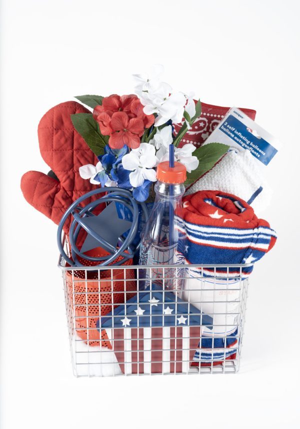 Introducing the Adult Gambling Night Basket: a wire basket filled with a red oven mitt, artificial red, white, and blue flowers, a blue jar opener, a clear water bottle with a red lid and straw, red and white dish towels, a rolled-up striped towel, and a small box adorned with an American flag design.