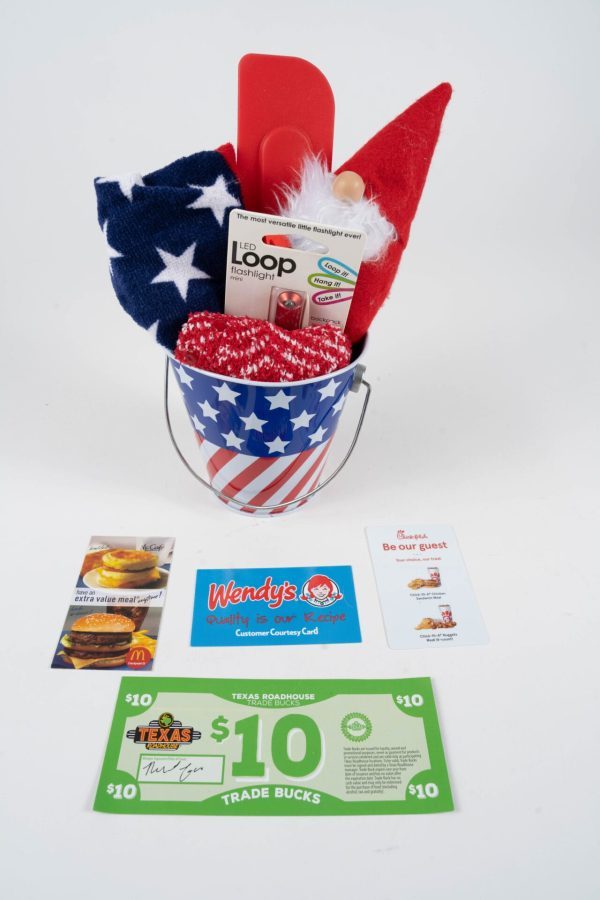 Introducing the Patriotic Pail with Free Food Certificate: a star-spangled collection featuring a red, white, and blue towel, kitchen utensils, an oven mitt, gift cards, restaurant coupons from Wendy's, Texas Roadhouse, McDonald's and more. Perfect for showcasing your patriotic spirit while enjoying great dining deals.