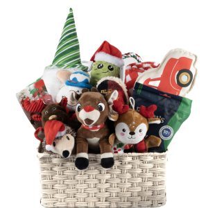 The Holiday Dog Pet Basket - Large is a festive gift basket brimming with Christmas-themed stuffed toys, including reindeer, Santa hats, a plush character in a green elf hat, and a toy truck. Wrapped presents and green packaging add to the cheerful display. The light-colored woven basket brings joy to any home or pet this season.