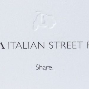 A white sign features the embossed outline of a scooter at the top. Below, black capital letters read "PIADA ITALIAN STREET FOOD," with the word "Share." centered in smaller black font underneath. Enjoy our protein-packed dishes or grab Piada BOGO Cards (includes protein) for your next meal!