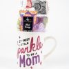 The Sparkle Mom Mug Gift Basket with Free Food Certificate includes a white ceramic mug adorned with the phrase "It takes a little sparkle to be a Mom" in pink and purple letters. The mug comes filled with a rolled colorful towel, a tube of blood orange body lotion, and a purple loofah mesh.