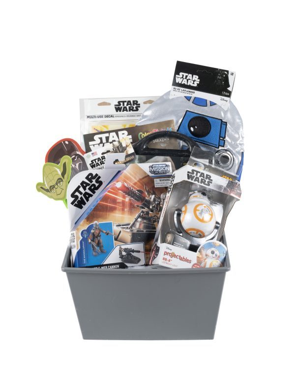 The Star Wars Gift Basket includes a variety of themed items such as a Yoda keychain, BB-8 and R2-D2 toys, stickers, a coloring activity book, and a Star Wars notebook. All these items are neatly arranged in a sleek gray rectangular container.