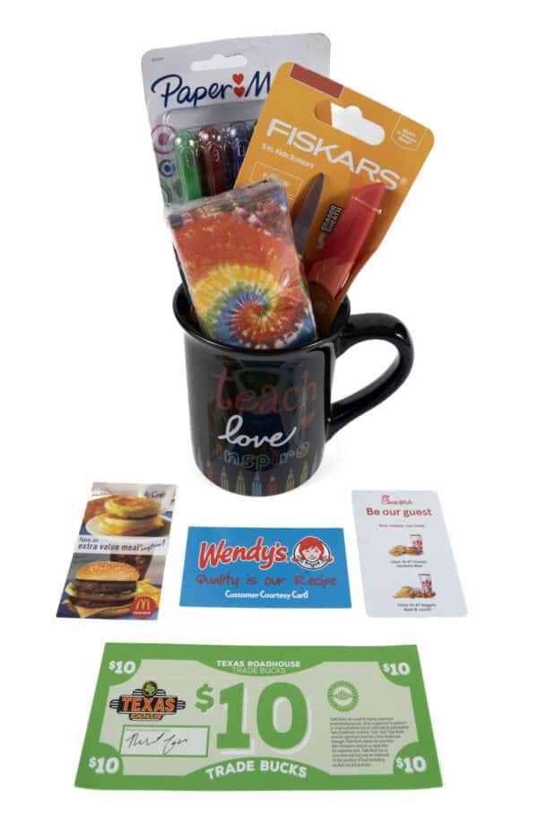 The Teach Love Mug Gift Basket with Free Food Certificate includes a black "Teach Love Inspire" mug accompanied by multicolored pens, orange scissors, and a tie-dye item. Surrounding the mug are free food certificates for McDonald's, Wendy's, and Texas Roadhouse.