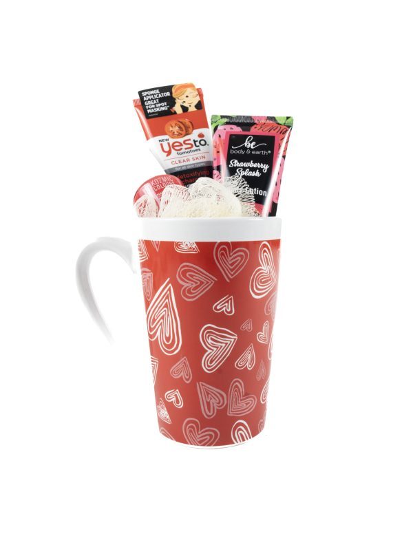 The Valentine's Day Hearts Mug with Free Food Certificate is filled with a bath pouf, a sachet of Yes To brand tomatoes clear skin acne-fighting paper mask, and a packet of Strawberry Crush body lotion. Perfect for Valentine's Day, the items are arranged neatly inside the mug.