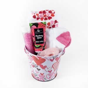 The Valentine's Day Pail with Free Food Certificate is a charming gift option, featuring a small pail adorned with heart designs, and includes a tube of strawberry-scented body lotion, pink bath salts, a small loofah, a pair of white socks with pink hearts, and another pair of white socks with red and pink paw prints—ideal for creating cozy Valentine's Day memories.