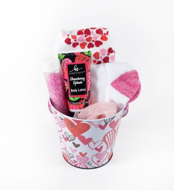 The Valentine's Day Pail with Free Food Certificate is a charming gift option, featuring a small pail adorned with heart designs, and includes a tube of strawberry-scented body lotion, pink bath salts, a small loofah, a pair of white socks with pink hearts, and another pair of white socks with red and pink paw prints—ideal for creating cozy Valentine's Day memories.